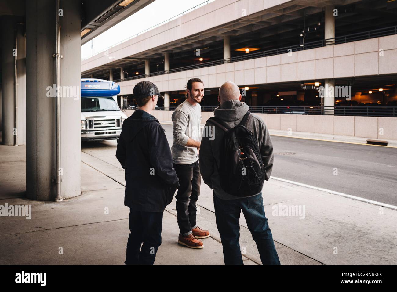 Vater und Söhne im Teenageralter warten am Flughafen auf den Shuttleservice Stockfoto