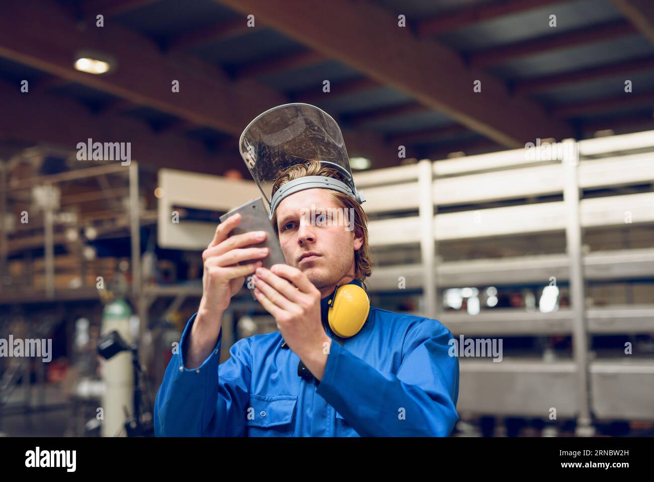 Fokussierter Mitarbeiter, der Maschinenteile im Werk untersucht Stockfoto