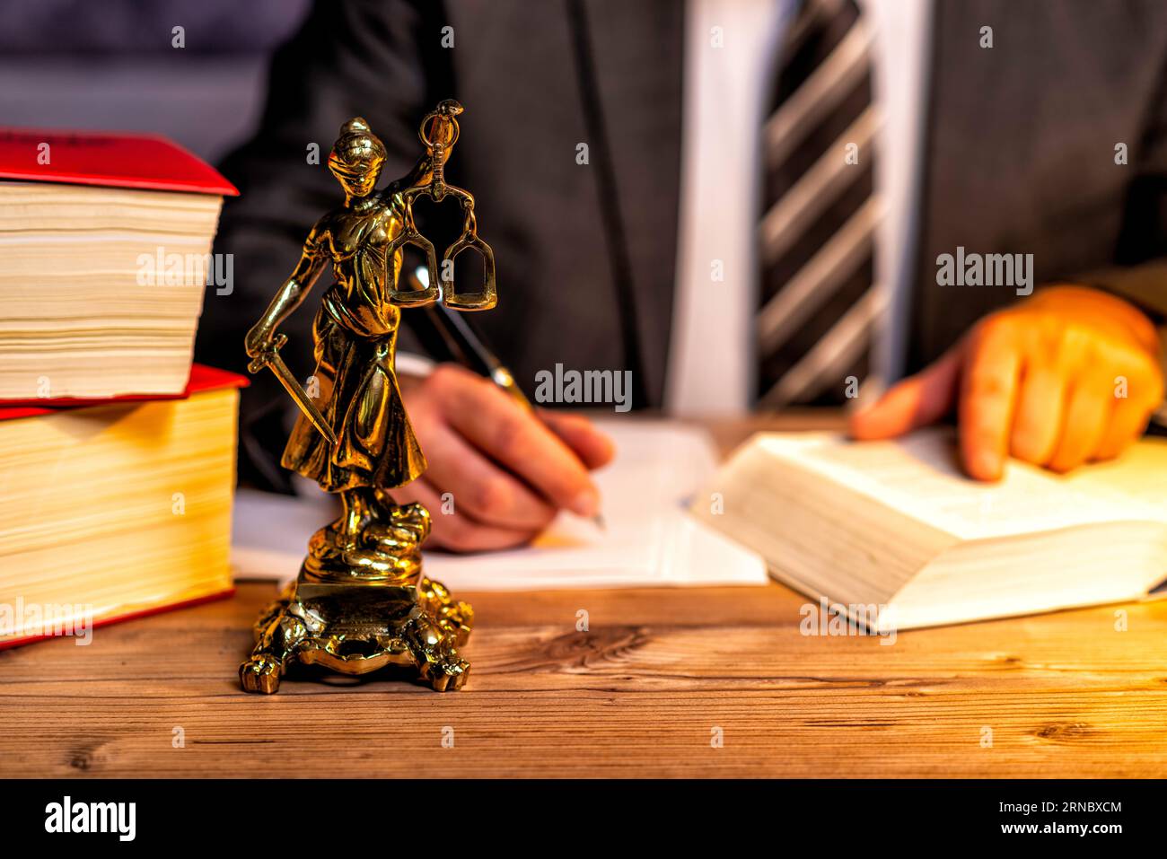 Kanzlei eines Rechtsanwalts mit Büchern und einer Statue von Lady Justice, Göttin Justitia, auf dem Schreibtisch Stockfoto