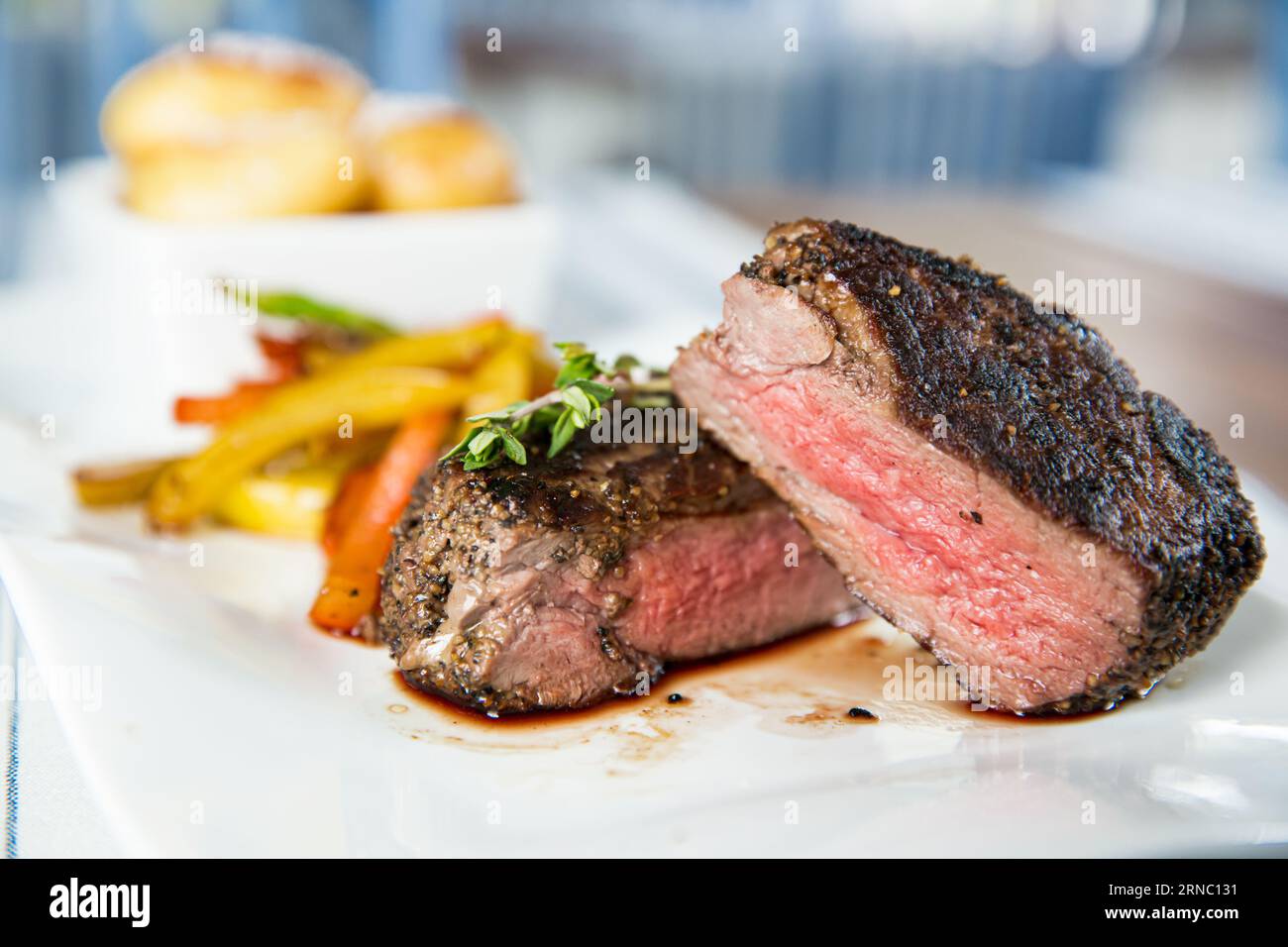 Appetitliches mittelseltenes, gegrilltes Rindersteak mit gebackenem Gemüse auf weißem Teller. Stockfoto