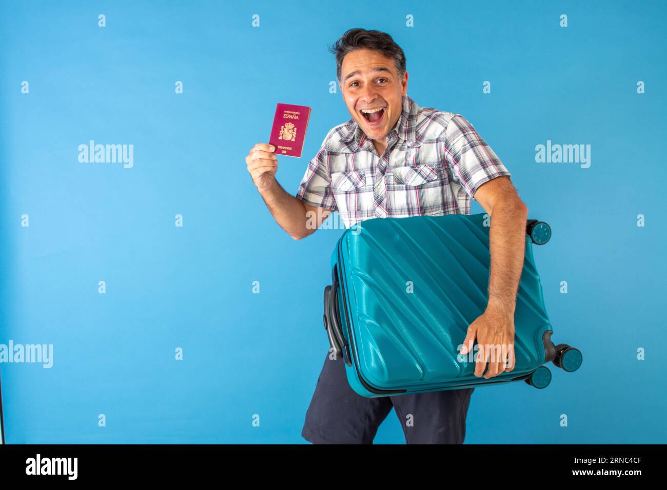 Mann in einem karierten Hemd trägt den Pass in der einen Hand und in der anderen den Koffer, der bereit ist, auf eine Reise zu gehen Stockfoto