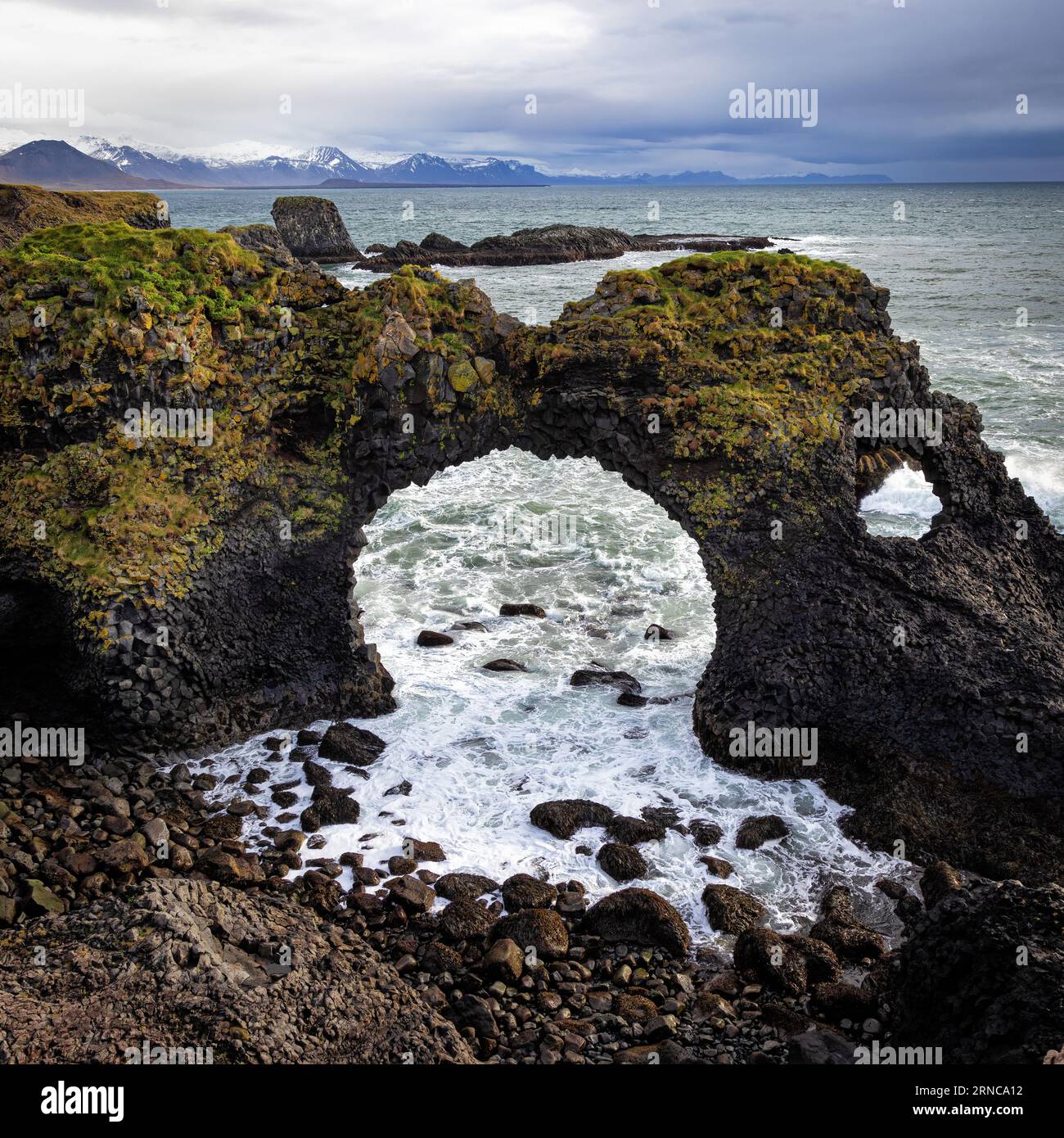 Flechten und Moos bedeckte Steinbrücke in Arnarstapi, Snaefellsness Peninsula, Island. Der Meeresbogen ist als Gatklettur oder Hellnar Arch bekannt. Stockfoto