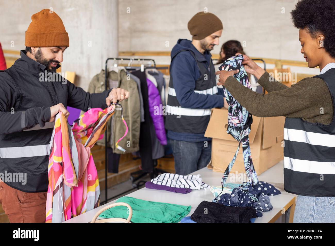 Männliche und weibliche Arbeiter sortieren recycelte Kleidung auf dem Tisch im Recyclingzentrum Stockfoto