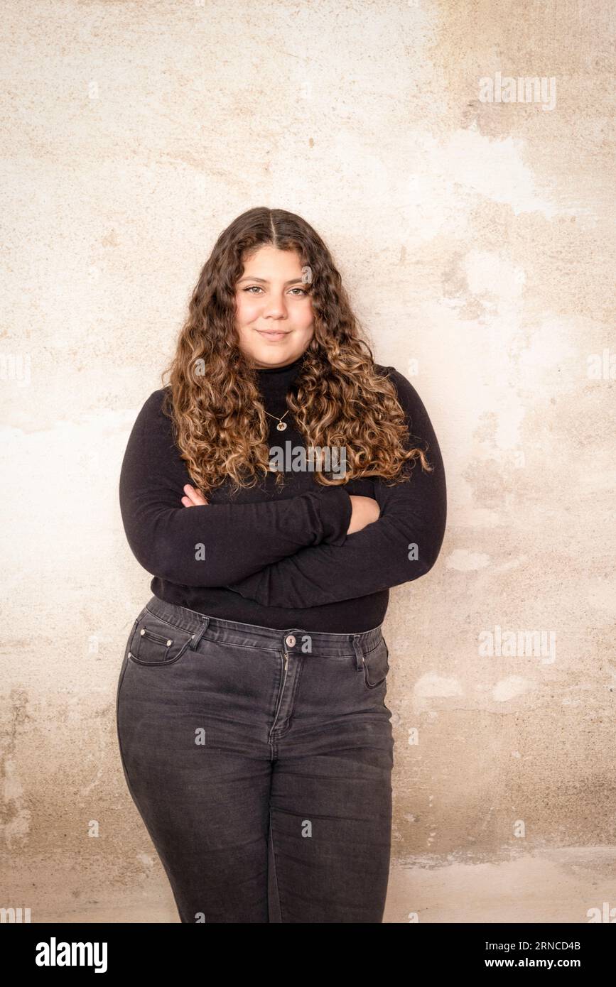 Porträt einer selbstbewussten Frau mit überkreuzten Armen in der Nähe der Mauer im Recyclingzentrum Stockfoto