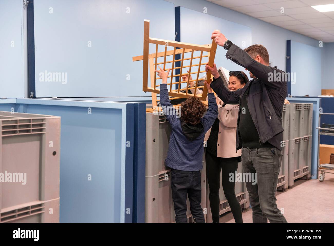 Glückliche Familie, die Holzabfälle im Recyclingzentrum entsorgt Stockfoto