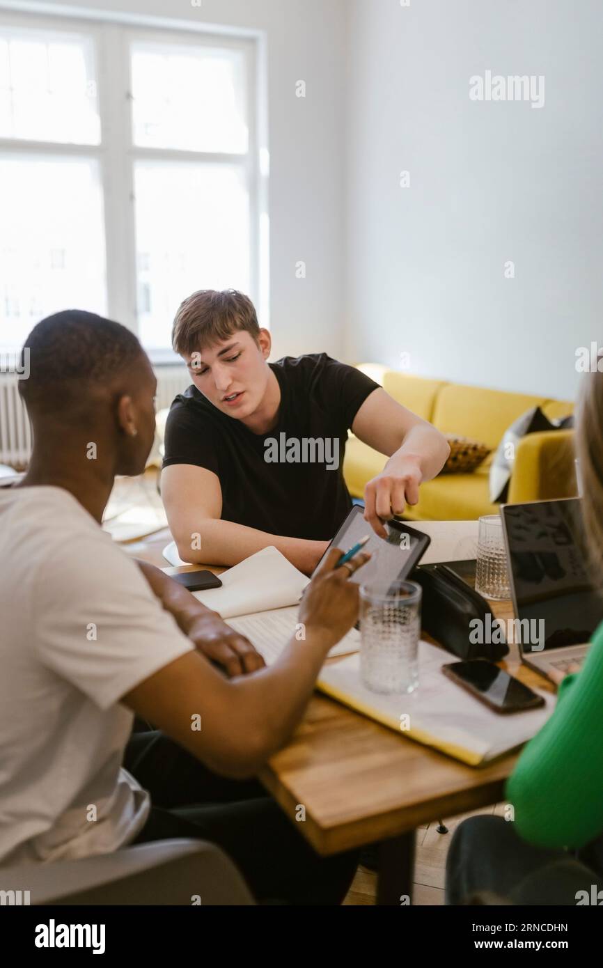 Männliche Freunde lernen zusammen, während sie zu Hause ein digitales Tablet verwenden Stockfoto