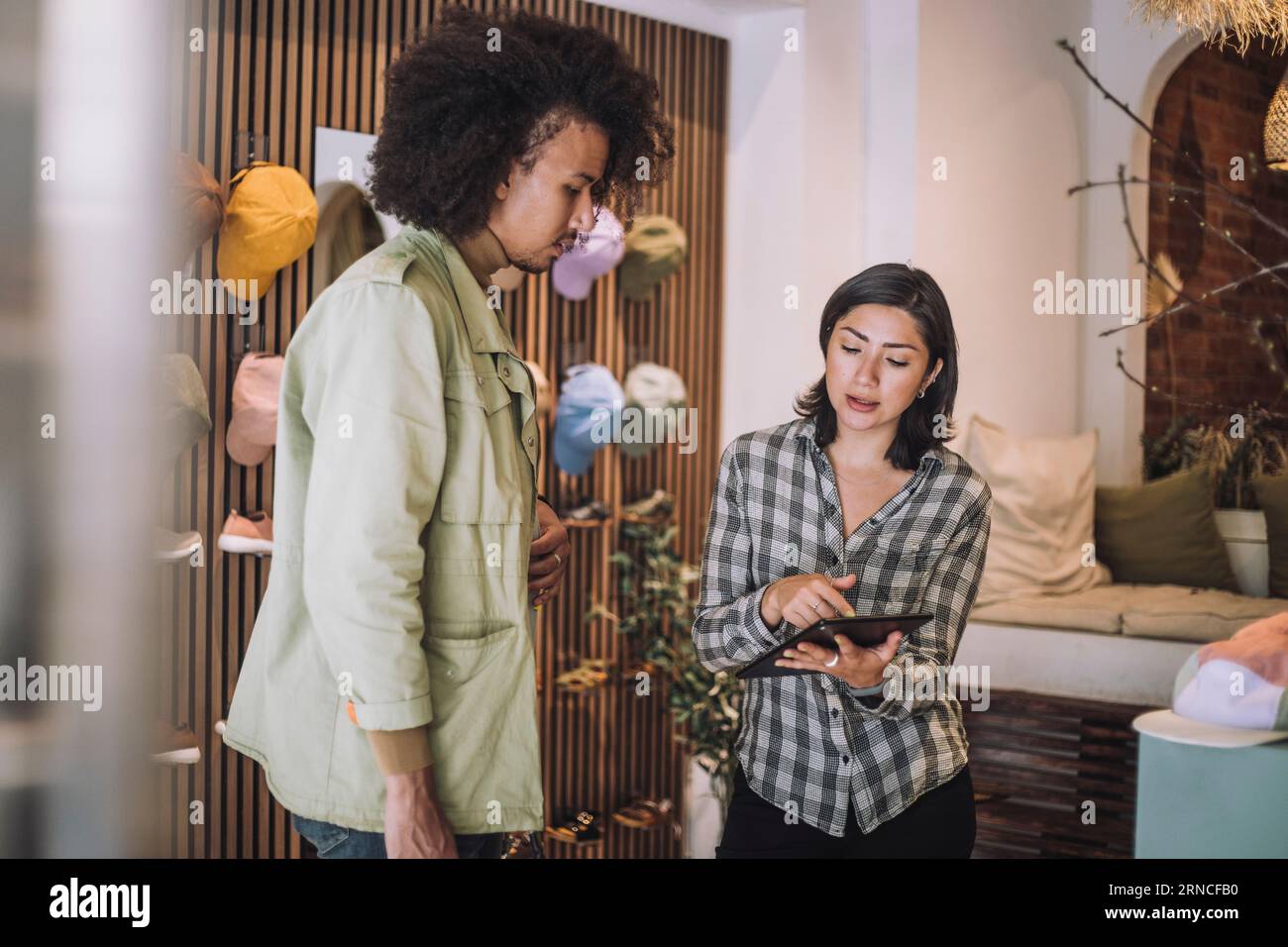 Verkäuferin, die ein digitales Tablet in der Modeboutique teilt Stockfoto