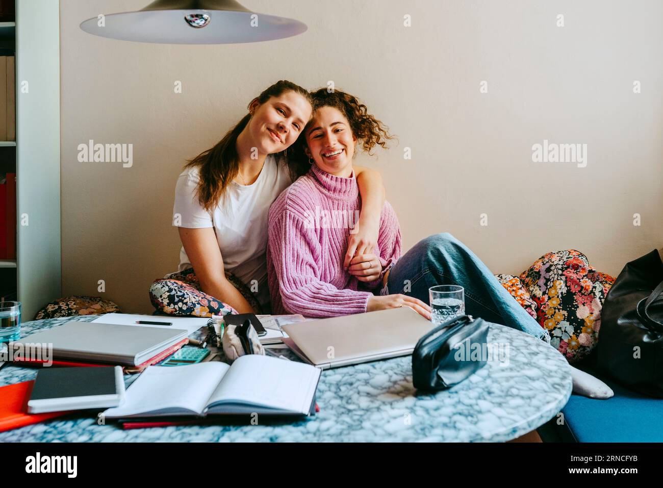 Porträt glücklicher junger Freundinnen, die zu Hause sitzen Stockfoto