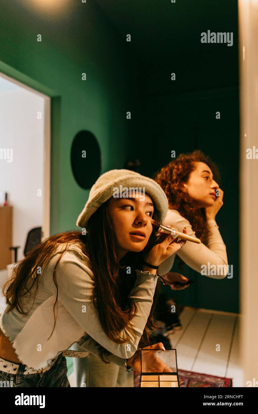 Junge Freundinnen, die sich zu Hause schminken Stockfoto