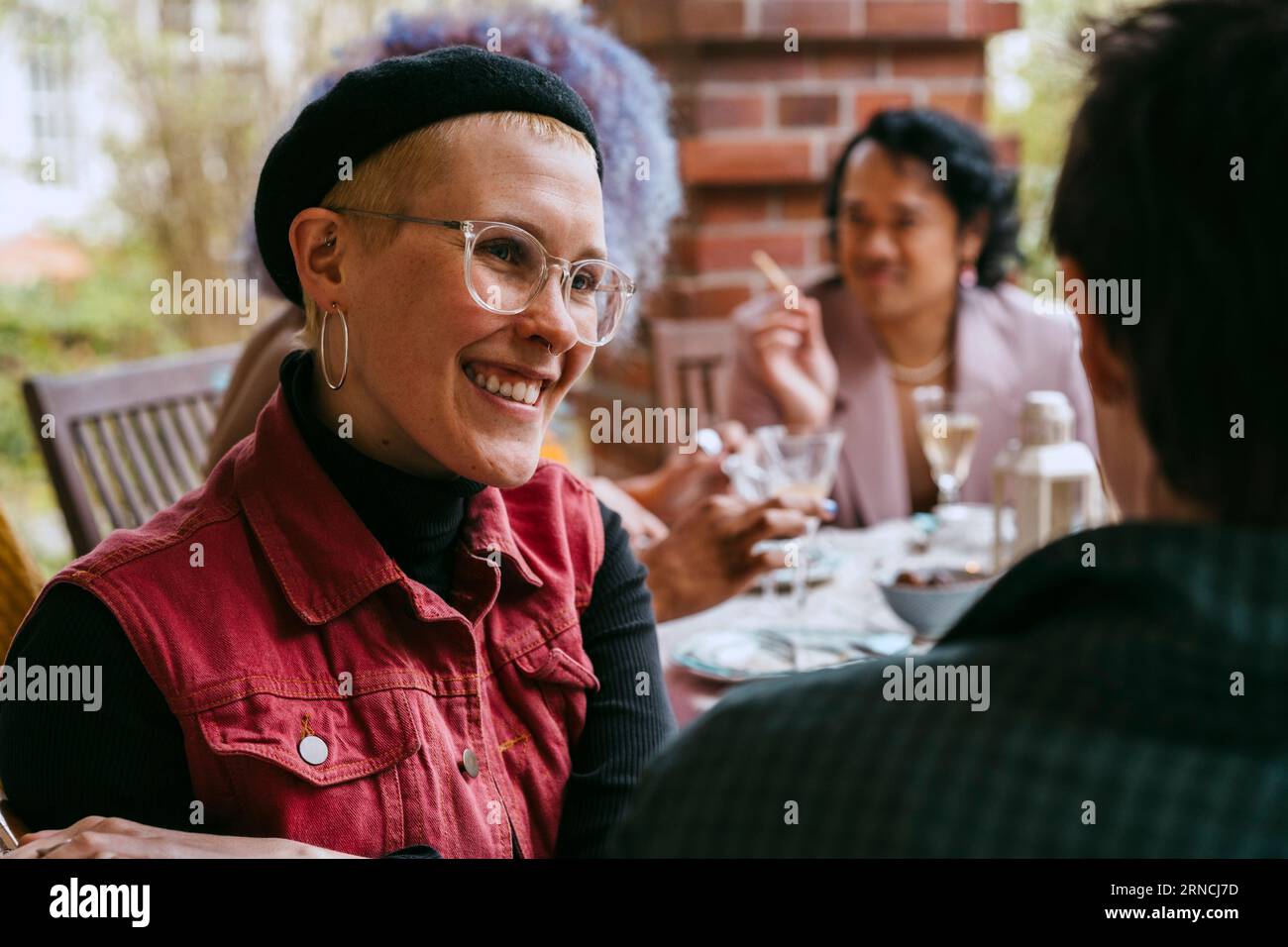Lächelnde schwule Frau, die mit einem Freund während der Party im Hinterhof spricht Stockfoto