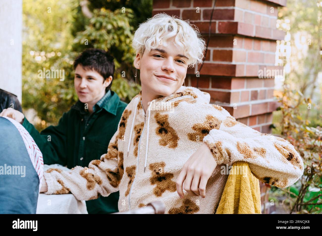 Porträt eines lächelnden schwulen Mannes mit weißen Haaren während einer Dinnerparty im Hinterhof Stockfoto