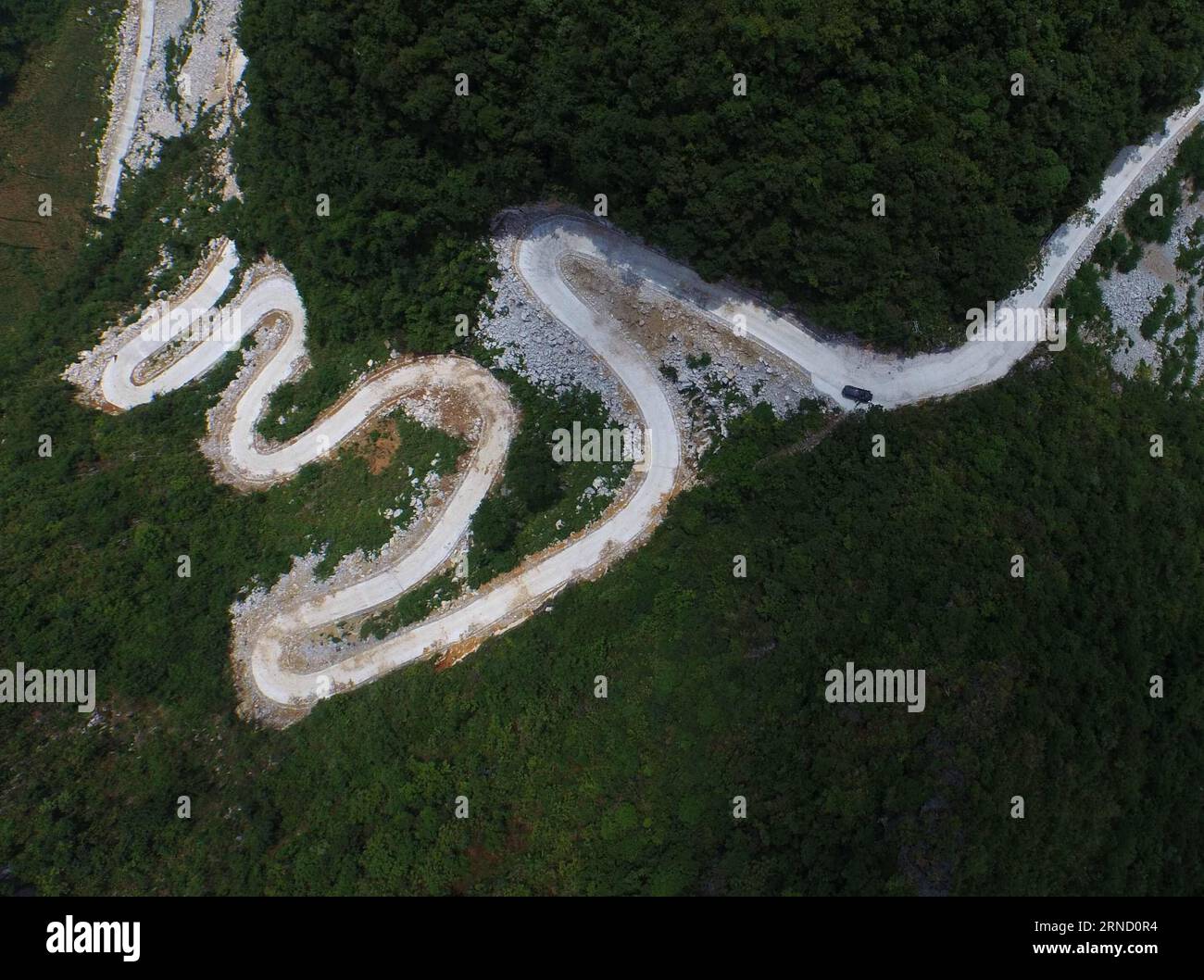 (160427) -- DAHUA, 27. April 2016 -- ein Luftbild, das am 13. Juli 2015 aufgenommen wurde, zeigt eine gewundene Straße in der Nähe des Nongliang-Dorfes der Qibainong-Gemeinde des autonomen Komitats Dahua Yao, des autonomen Komitats Guangxi Zhuang in Südchina. Die Städte Qibainong und Bansheng, die Hunderte von Vertiefungen mit einer durchschnittlichen Tiefe von 105 Metern haben, befinden sich zwischen Bergen mit einer Höhe von 800-1000 Metern. Die Pro-Kopf-Anbauflächen liegen jedoch unter 0,25 mu (0,017 Hektar) in diesem felsigen Gebiet, und die Bewohner müssen hier durch Niederschläge Zugang zu trinkbarem Wasser haben. Seit den 1990er Jahren hat die Kommunalregierung eine eingeführt Stockfoto