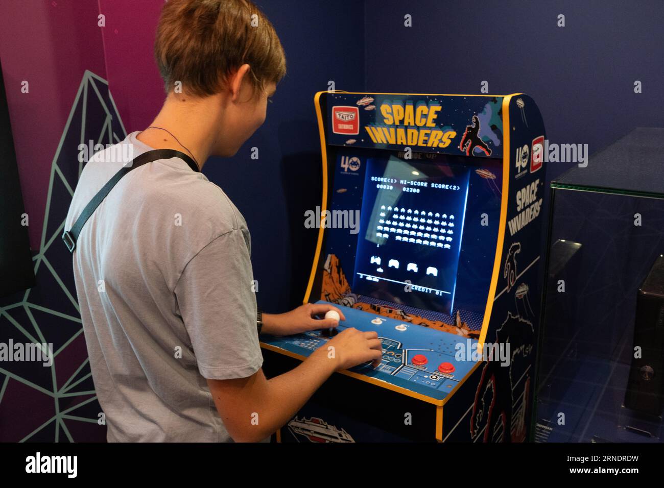 Raumeindringlinge Taito Spielmaschine. Simple Space Arcade in einem alten 8-Bit-Retro-Video. Boy spielt den klassischen Spielautomaten. Warschau, Polen - 28. Juli 2023. Stockfoto