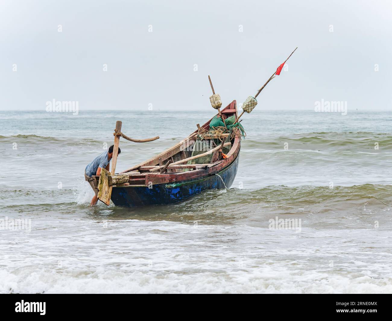 Fisherman startete sein Boot gegen Wind und hohe Wellen in Sam Son Beach, Thanh Hoa, Vietnam Stockfoto