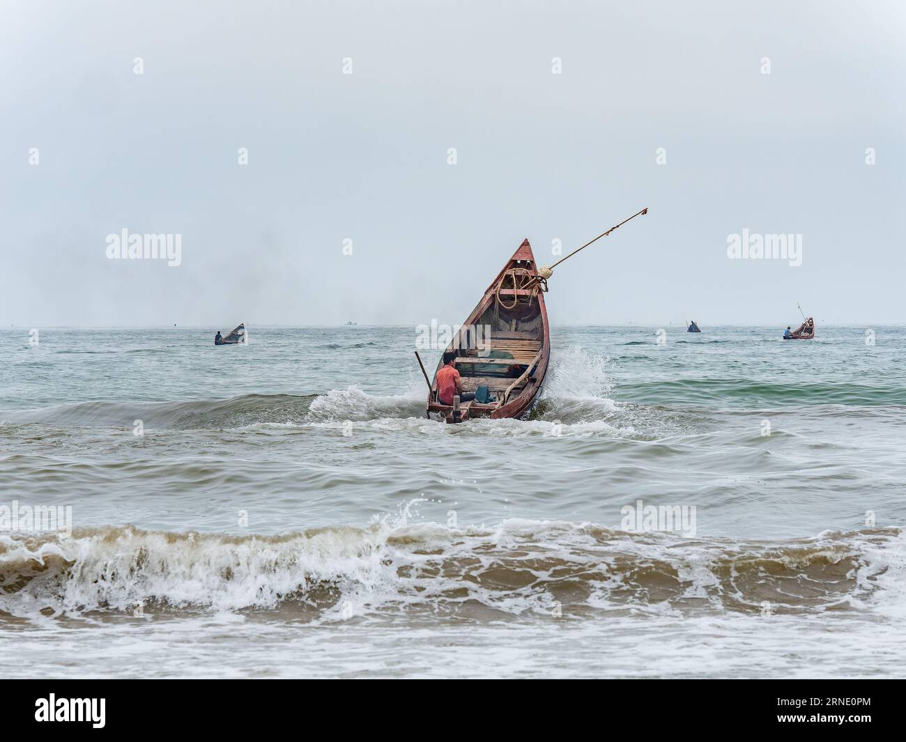 Fisherman startete sein Boot gegen Wind und hohe Wellen in Sam Son Beach, Thanh Hoa, Vietnam Stockfoto