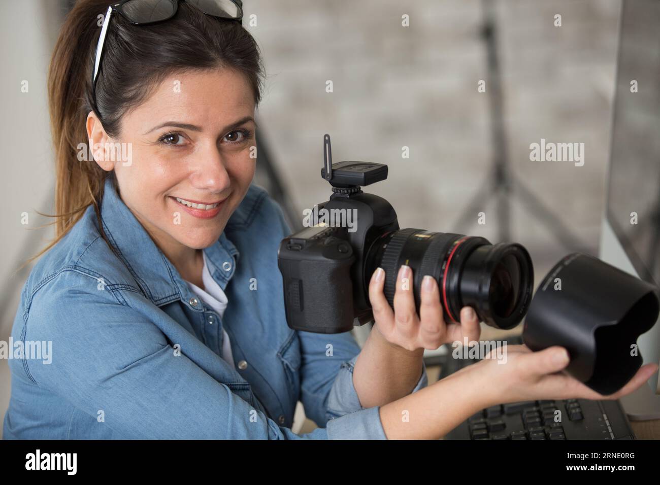 Weibliche Fotografin fügt Objektivbefestigung zur Kamera hinzu Stockfoto