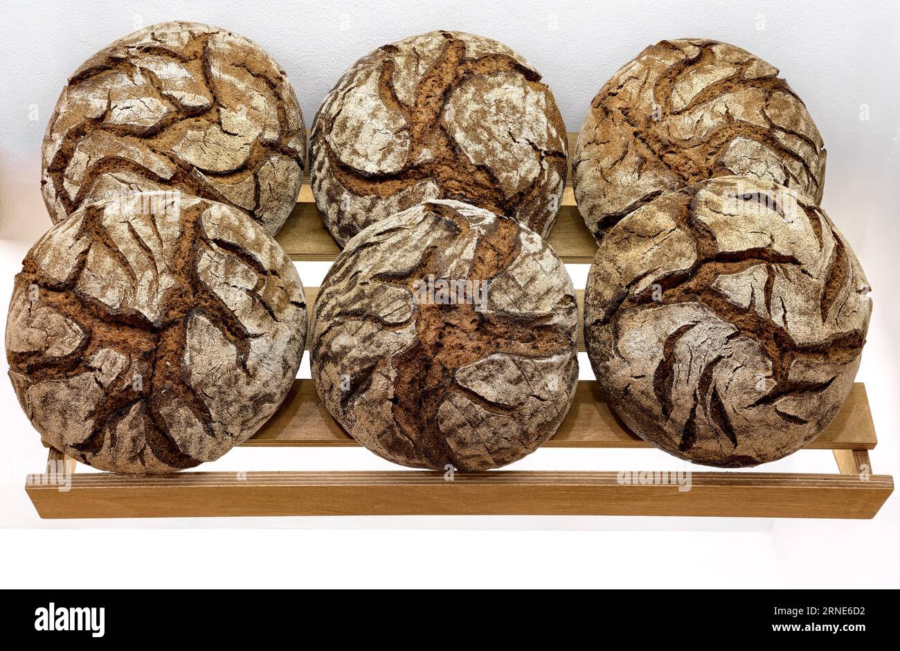 Runde Brotlaibe von dunklem Roggenbrot auf dem Regal in der Bäckerei. Großes Rundbrot isoliert auf weißem Hintergrund. Stockfoto