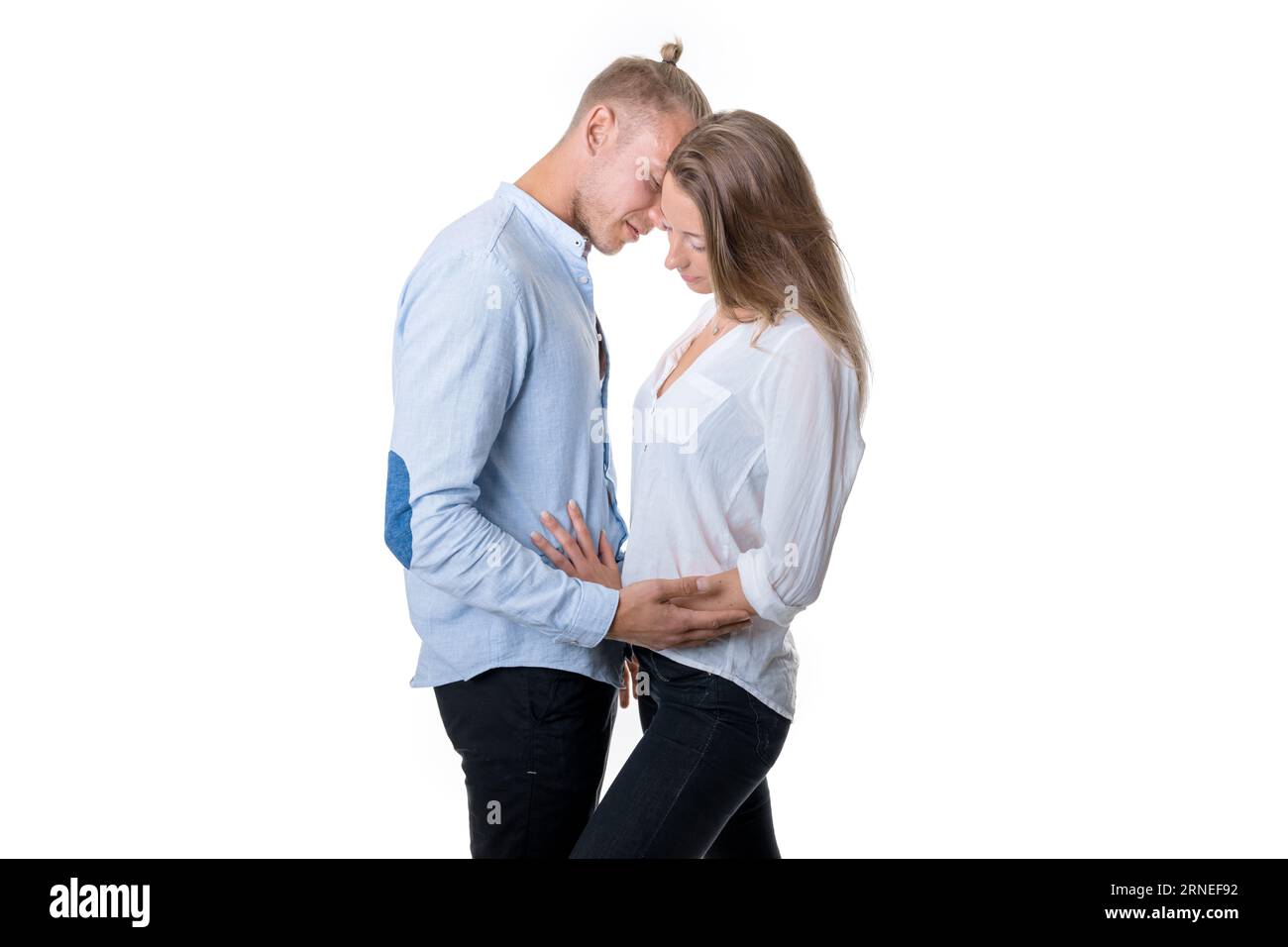 Junge Paare isoliert auf weißem Stand und Umarmung, während sie direkt vor einem liebevollen Kuss in dieser romantischen Situation sind Stockfoto