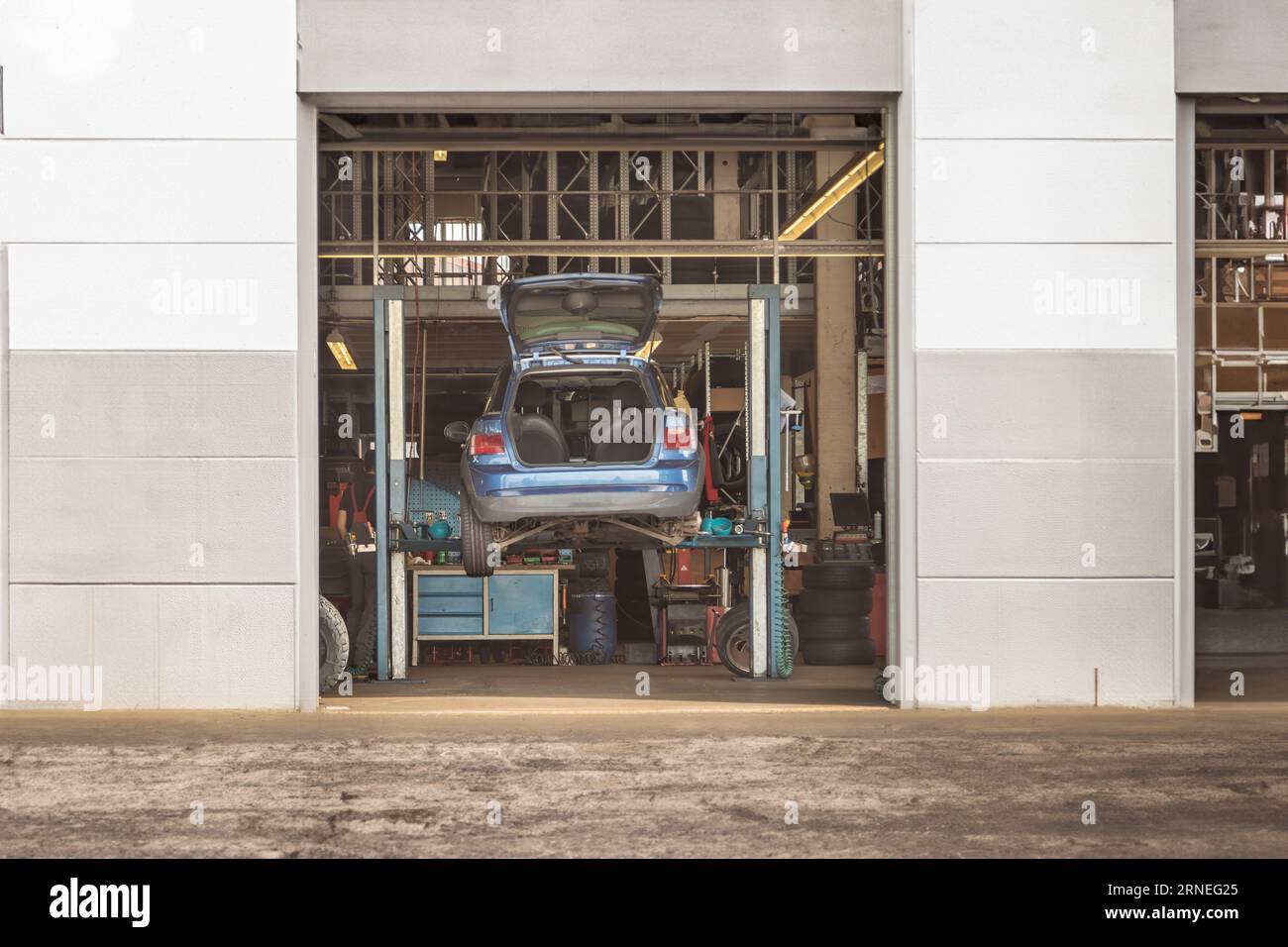 Kfz-Wartung: Fahrzeug auf Hebebühne in Garage für Reparatur und Inspektion, Mechanikerwerkstatt mit erhöhtem Fahrzeug Stockfoto