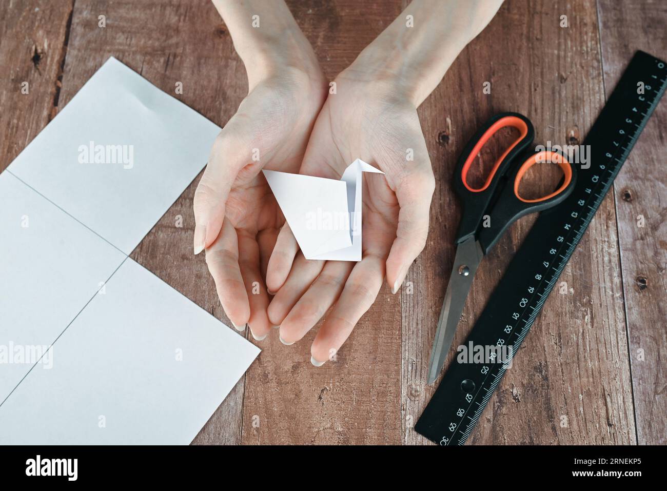 Hände einer älteren Frau falten Origami-Papier. Erstellen eines Origami-Papierkrans, Nahaufnahme Stockfoto