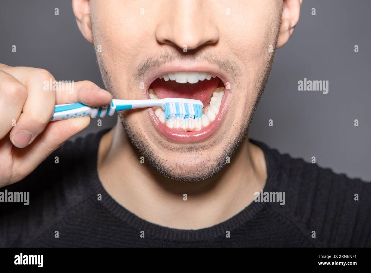 Mann mit Zahnbürste auf der Rückseite seiner unteren Zähne bürstet die Rückseite gegen Karies und Bakterien Stockfoto