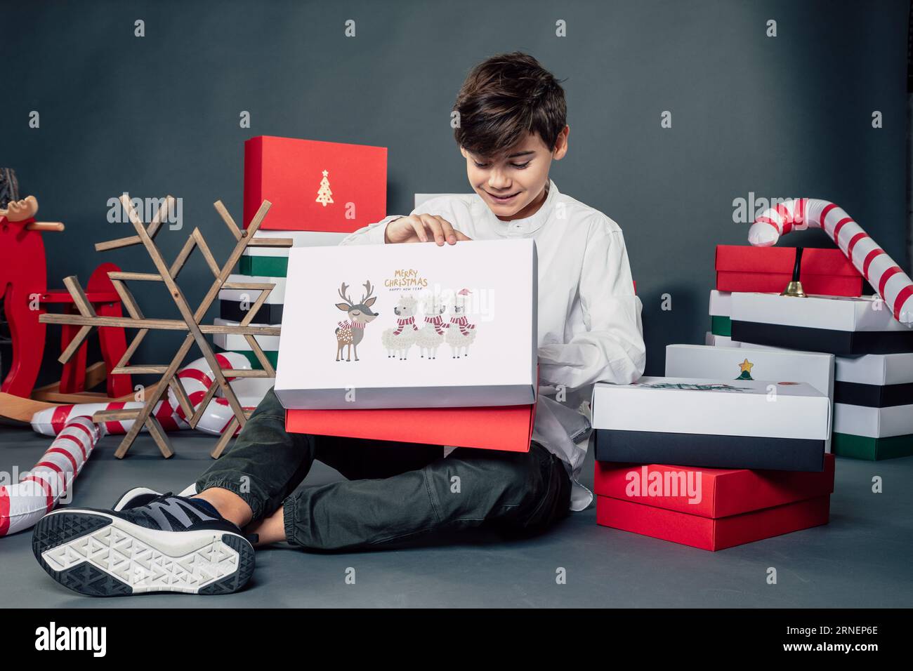 Teen boy packen Geschenke am weihnachtsmorgen mit hohen Erwartungen und glückliches Lächeln auf seinem Gesicht aus, während Sie die Box öffnen und in Geschenke schauen Stockfoto