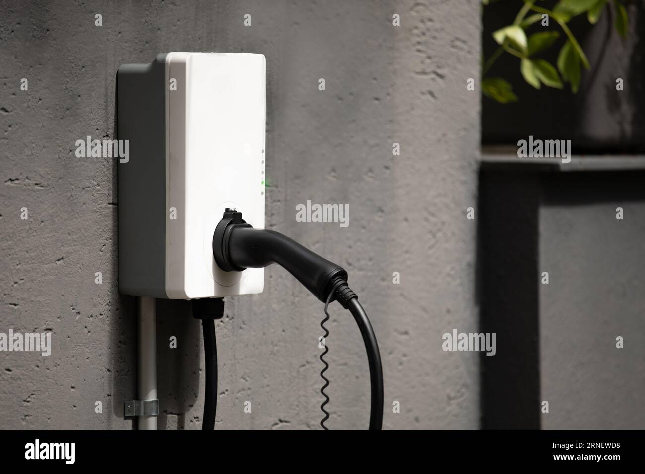 Steckerhalter für Ladestation für Wandmontage mit Kabel an der Wandbox, die an der Betonwand montiert ist, bereit zum Laden und Betanken von Elektroautos mit Power-in Stockfoto