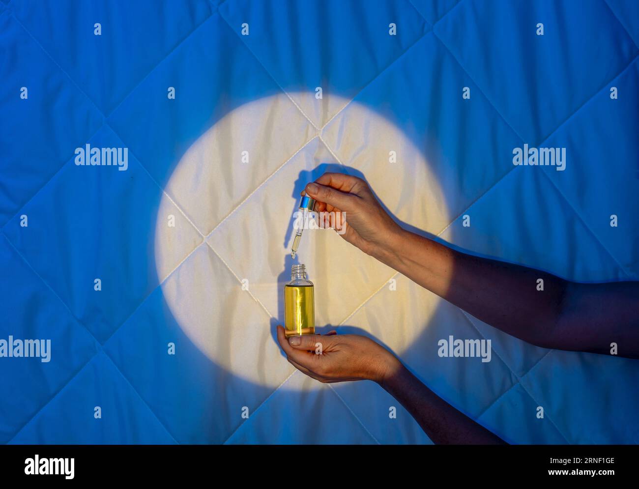 Beruhigende Schlummer: Wissenschaft hinter Schlafölen, Melatonin und Sweet Dreams, Tropfer mit Öl in der Hand Stockfoto