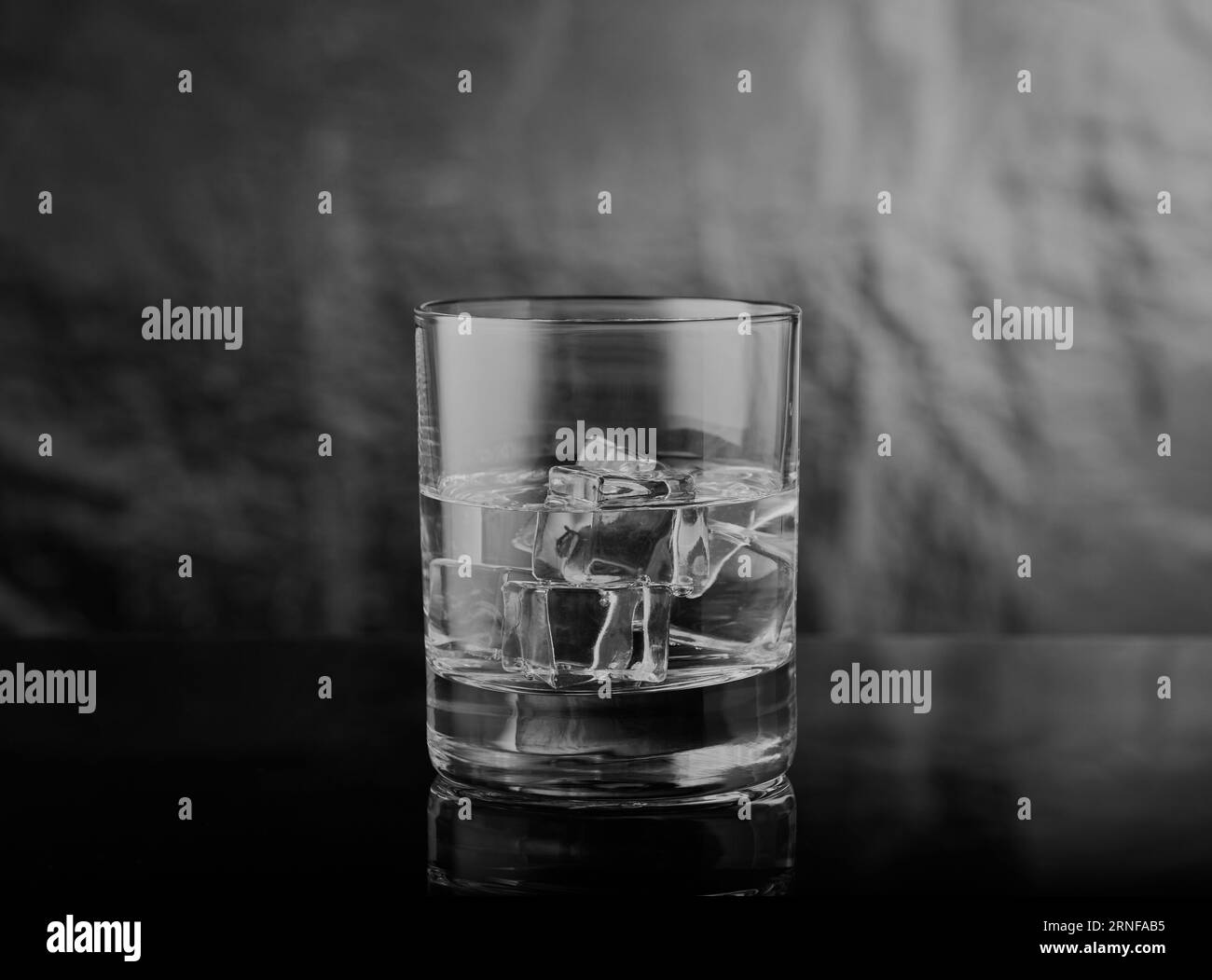 Schwarz-weiß-Bild von Whisky-Glas mit Spirituosen und Eis im Glas mit einem stimmungsvollen Gefühl. Stockfoto