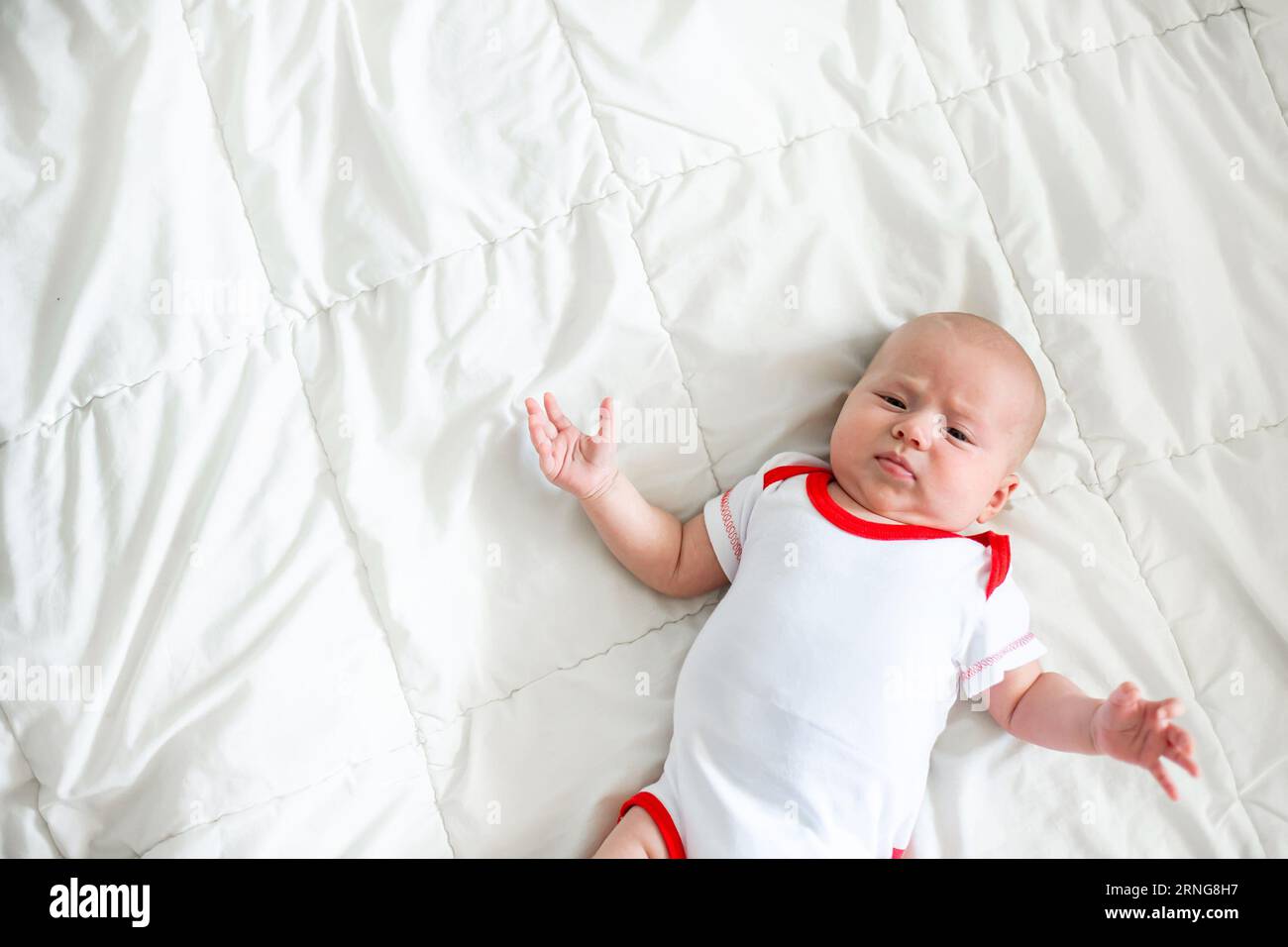 Kleines 2 Monate altes Baby, das auf einer weißen Decke in einem Kinderbett liegt Stockfoto