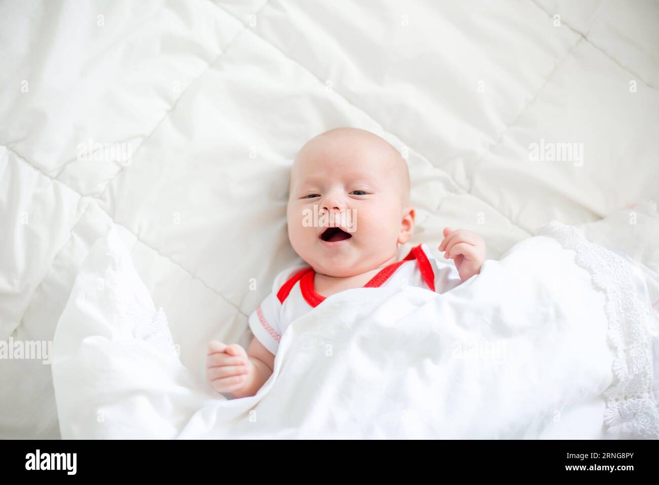 Gefahr für das Kind. Neugeborenes unter einer Erwachsenendecke auf dem Bett der Eltern Stockfoto