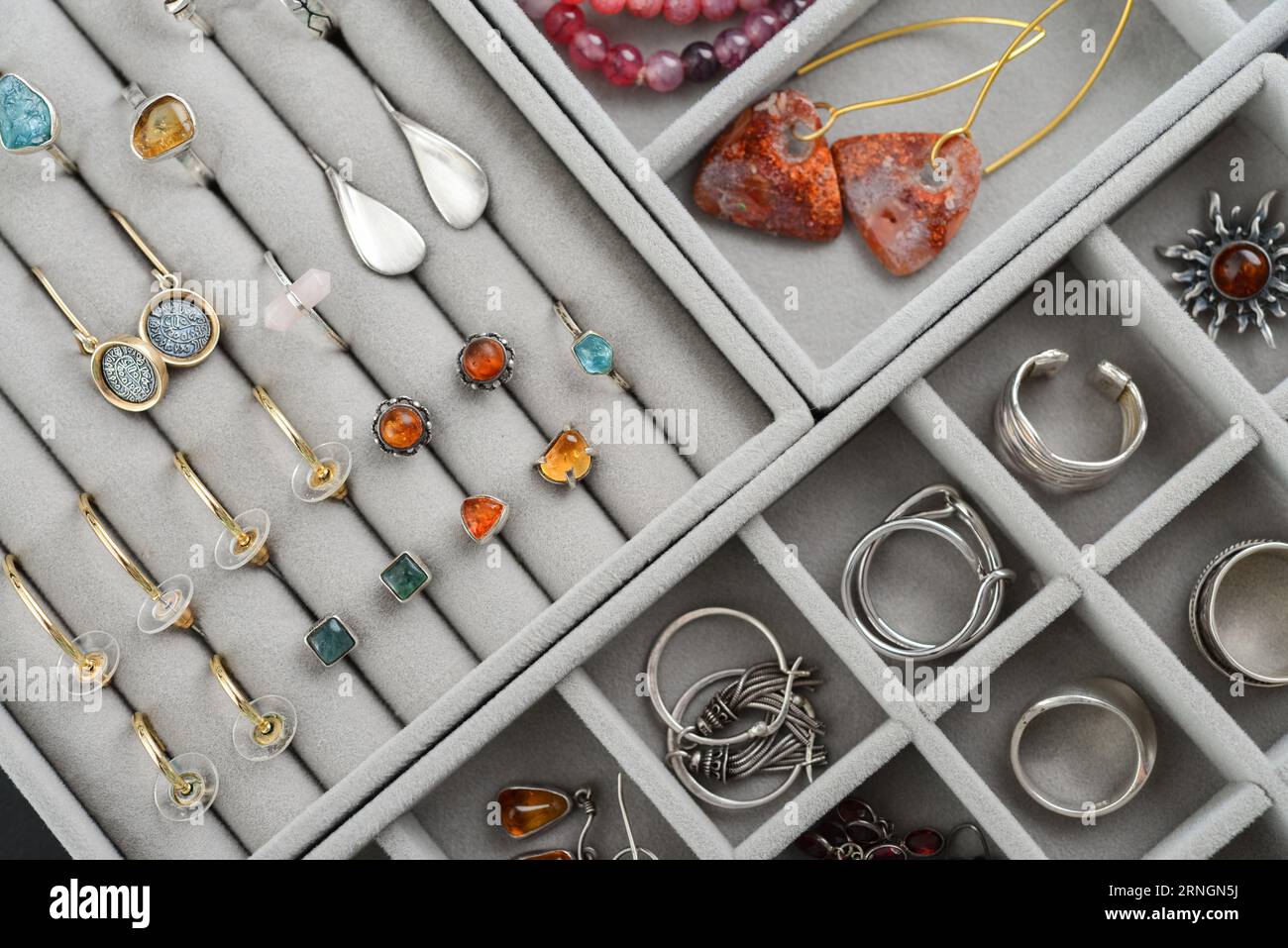 Grauer Samtschmuckorganisator mit verschiedenen Silber- und Goldringen, Ohrringen und Armbändern, Draufsicht Stockfoto