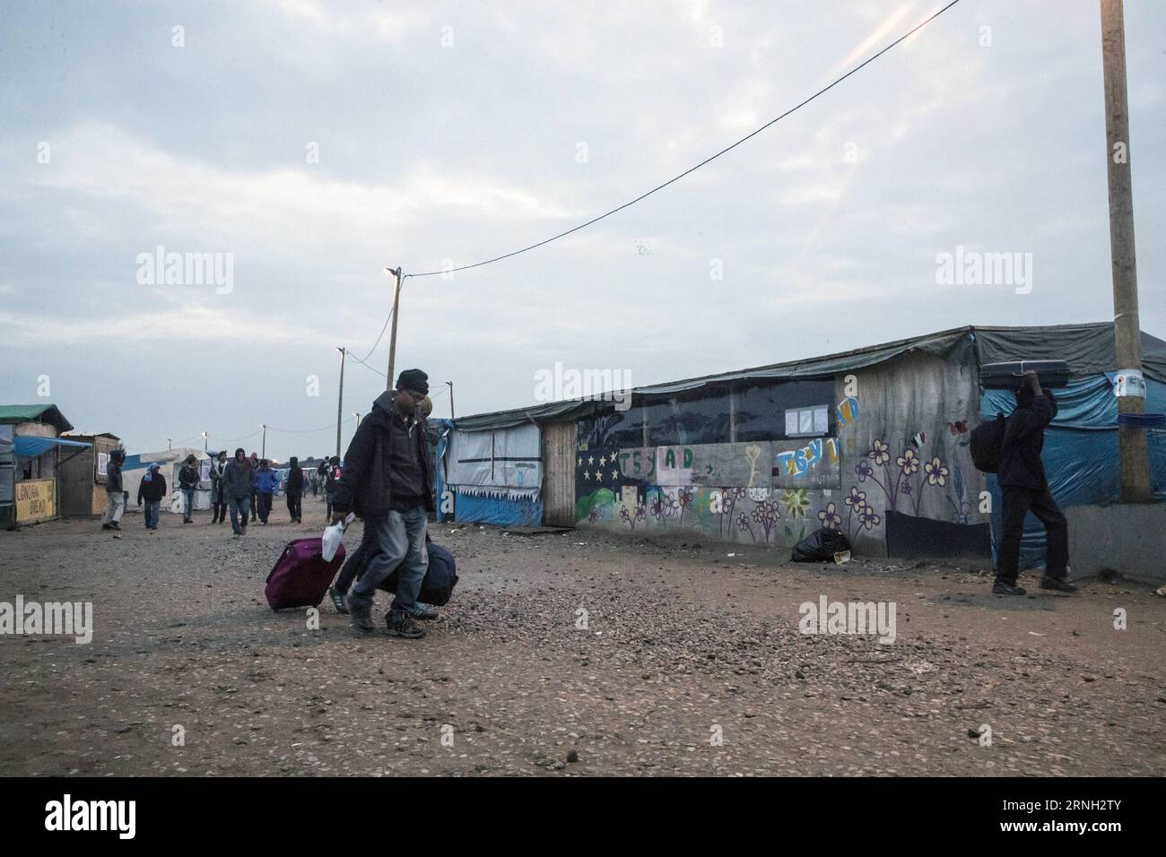 (161024) -- CALAIS (FRANKREICH), 24. Oktober 2016 -- Migranten mit ihren Koffern verlassen am 24. Oktober 2016 die Sackgasse im Norden von Calais, Frankreich. Frankreich hat am Montag damit begonnen, in einer ruhigen und kontrollierten Art und Weise die kleine Stadt im Norden von Calais zu räumen, in der etwa 9.000 Migranten leben, sagte der französische Innenminister Bernard Cazeneuve. (Sxk) FRANCE-CALAIS-MIGRANTS-EVAKUIERUNG JohnxFiddler PUBLICATIONxNOTxINxCHN 161024 Calais France OKT 24 2016 Migranten mit ihren Koffern verlassen die Shanty Town in Nord-Calais Frankreich AM OKT 24 2016 Frankreich hat AM Montag damit begonnen, einzulösen Stockfoto