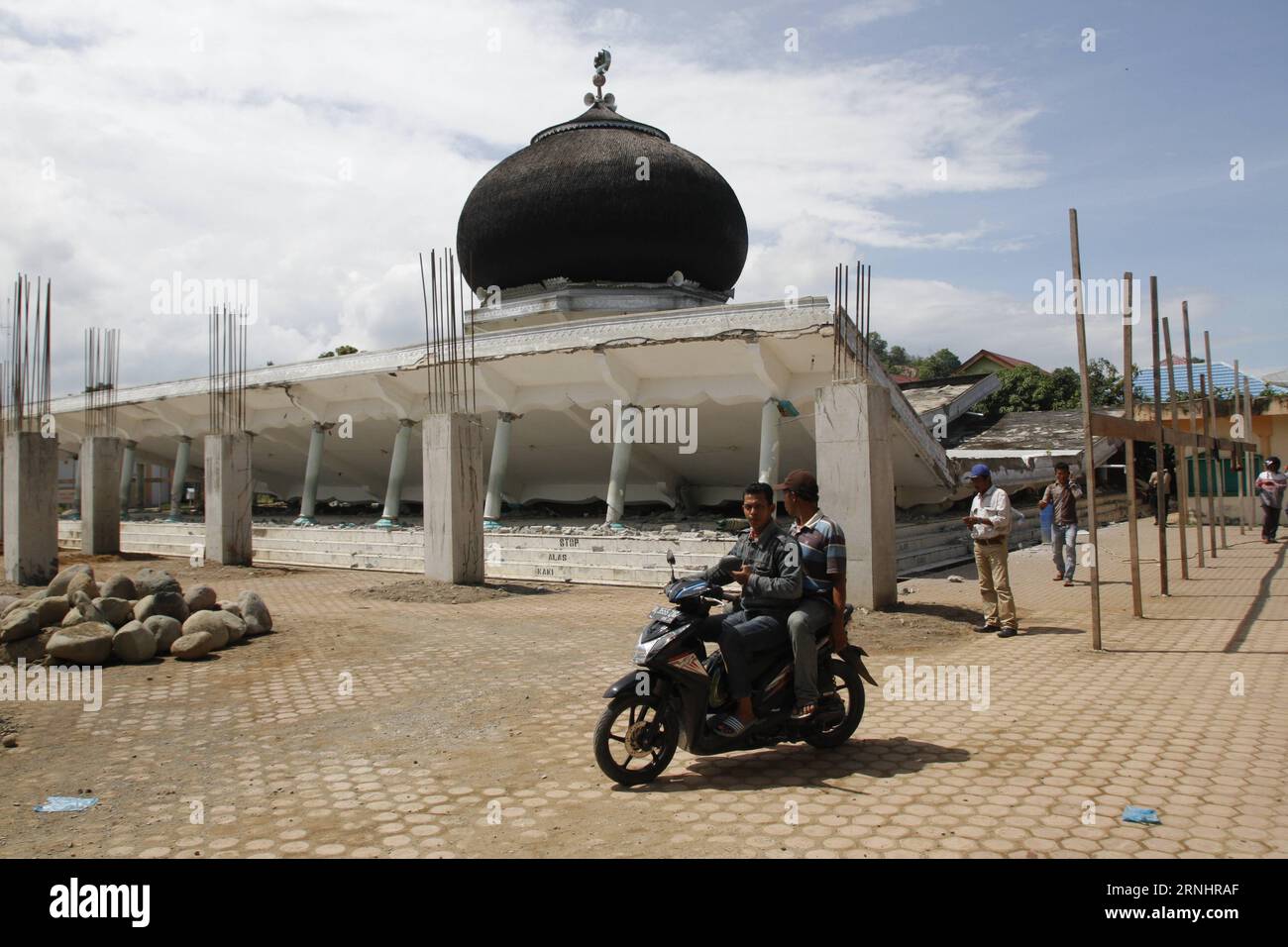 Erdbeben in Indonesien (161207) -- ACEH, 7. Dezember 2016 -- Menschen passieren die Ruinen einer Moschee im vom Erdbeben betroffenen Bezirk Pidie Jaya, Aceh, Indonesien, 7. Dezember 2016. Mindestens 97 Menschen wurden getötet und mehr als 600 andere litten an Wunden, nachdem ein mächtiges und flaches unterland-Beben die westindonesische Provinz Aceh am Mittwoch getroffen hatte, sagten hochrangige Militäroffiziere und Katastrophenschutzbeamte. )(gl) INDONESIA-ACEH-BAKE Junaidi PUBLICATIONxNOTxINxCHN Erdbeben in Indonesien Aceh DEC 7 2016 Prominente Pass die Ruinen einer Moschee in Quake trafen Jaya District Aceh Indonesien DEC 7 2016 mindestens Stockfoto