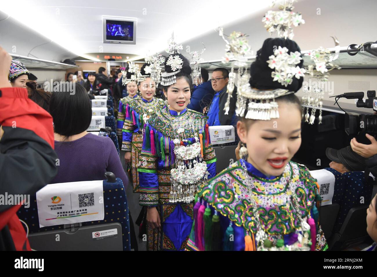 (161228) -- GUIYANG, 28. Dezember 2016 -- Passagiere der Miao-Volksgruppe singen Volkslieder auf einem Zug, der auf der Hochgeschwindigkeitsbahn Shanghai-Kunming fährt, 28. Dezember 2016. China hat am Mittwoch eine der längsten Hochgeschwindigkeitsbahnen der Welt in Betrieb genommen, die die wohlhabende Ostküste des Landes mit dem weniger entwickelten Südwesten verbindet. Die Shanghai-Kunming-Linie - 2.252 km lang - durchquert die fünf Provinzen Zhejiang, Jiangxi, Hunan, Guizhou und Yunnan und verkürzt die Reisezeit von Shanghai nach Kunming von 34 auf 11 Stunden, laut China Railway Corporation. ) (WYO) XINHUA INSIGHT CHINA-HI Stockfoto