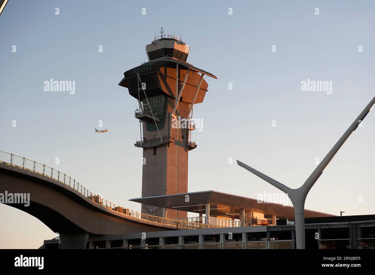 Ein abfliegendes Flugzeug fliegt am Kontrollturm am Flughafen LAX vorbei und über Gleise, die zu einem Bahnhof für Metro Rail-Passagiere in Los Angeles, CA, USA führen Stockfoto