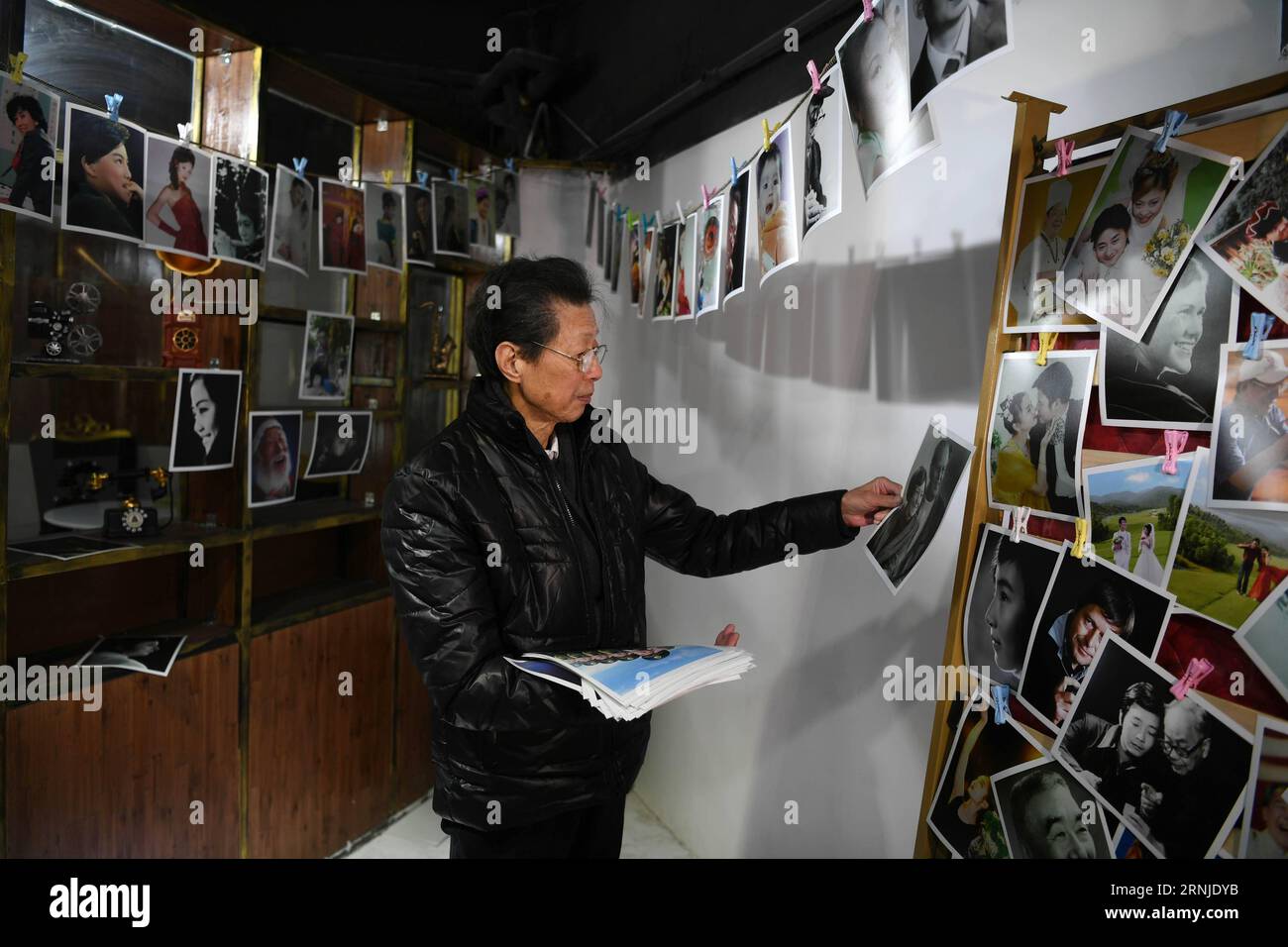 (170119) -- CHANGSHA, 19. Januar 2017 -- der Porträtfotograf Jiang Xingen sieht alte Porträts während seiner Ausstellung in Changsha, Provinz Hunan, 13. Januar 2017. In einem altehrwürdigen Fotostudio namens Arc de Triomphe findet vor kurzem eine besondere Fotoausstellung statt, in der Hoffnung, dass sie identifiziert werden könnten. Alle 300 nicht beanspruchten Fotos wurden in den letzten 60 Jahren von Jiang Xingen gemacht. ) (wx) CHINA-CHANGSHA-UNCLAIMED PORTRAITS-EXHIBITION (CN) LixGa PUBLICATIONxNOTxINxCHN Changsha 19. Januar 2017 Portrait Photo Jiang sieht alte Porträts während seiner Ausstellung in Changsha Central China S Hunan Provinz Stockfoto