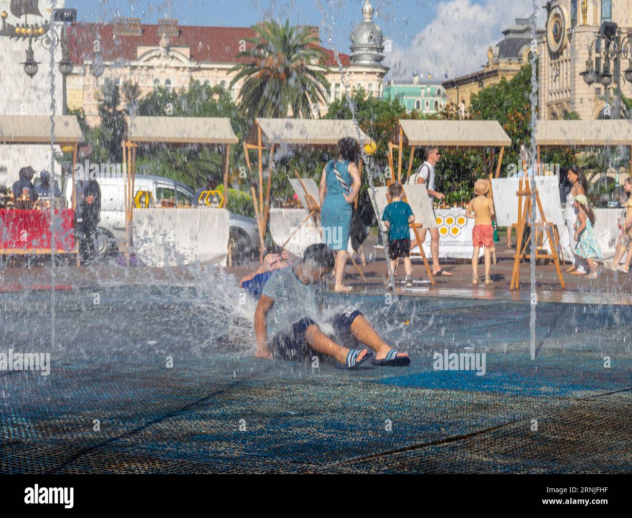 Batumi, Georgia. 08.19.2023 Kinder spielen im Springbrunnen. Kinderspiele in der Stadt. Erlösung aus der Hitze im Wasser. Kindliches Konzept. Ch.-B. Stockfoto