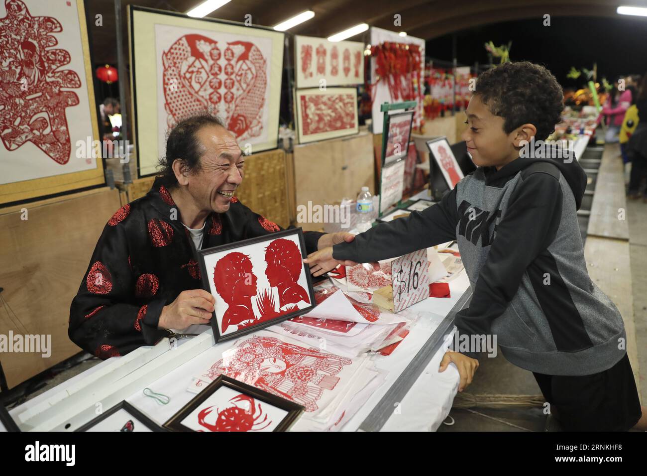 (170402) -- BOCA RATON, 2. April 2017 -- Li Baogui, ein Papierschneider, übergibt einem Kind während eines Laternenfestivals im Sunset Cove Amphitheater in Boca Raton, Florida, USA, 24. März 2017 ein Kunstwerk. Sugar Drawing, eine traditionelle chinesische Volkskunst, die heißes Karamell verwendet, um zweidimensionale Figuren zu kreieren, gehört zu den vielen Volkskunst, die vom 24. Februar bis 9. April beim Chinese Lantern Festival im Palm Beach County, einem Paradies für Urlauber in Südflorida, ausgestellt wird. ) (zy) U.S.-BOCA RATON-CHINESE FOLK ARTS WangxYing PUBLICATIONxNOTxINxCHN Boca Raton 2. April 2017 Left a Paper Stockfoto