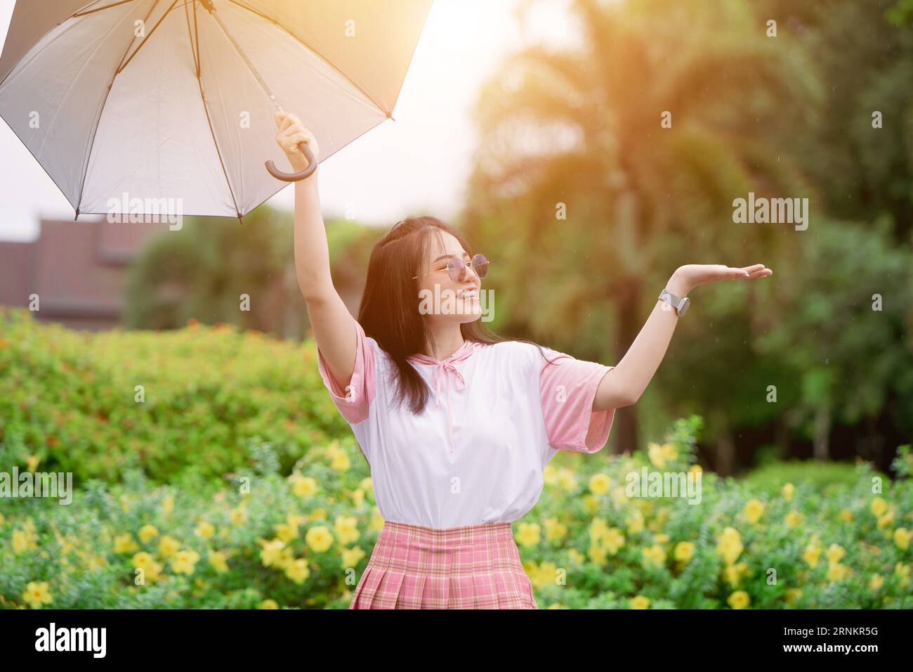 Glücklicher süßer asiatischer Teenager mit Regenschirm-Prätect aus Regen in der Regenzeit oder uv-Sonnenlicht im Sommer Stockfoto