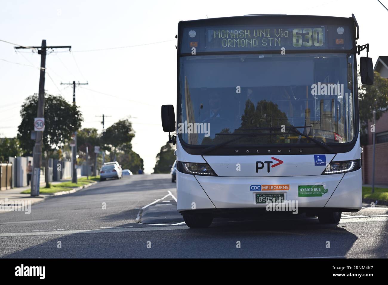 Vorderansicht eines von der CDC Melbourne betriebenen Volgren-Hybridbusses auf der Route 630 zur Monash University, der durch eine Kreuzung in den Vororten führt Stockfoto