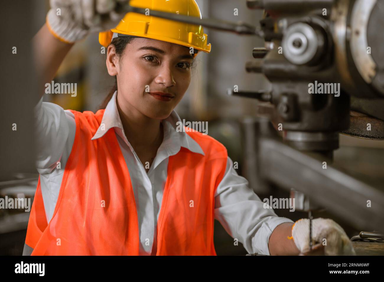 Glückliche junge asiatische Arbeiterin mit Schwermetallmaschinen-Drehmaschine, Fräsfabrik Stockfoto