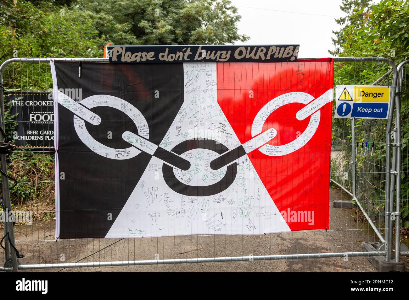 Himley, Staffordshire, Großbritannien. September 2023. Vier Wochen nach dem Abbrennen des berühmten Crooked House Pub werden Protestschilder und die Flagge des Schwarzen Landes angebracht, um den Wiederaufbau des Grundstücksgebäudes an derselben Stelle zu unterstützen. Die Flagge des Schwarzen Landes wird unterzeichnet und mit Unterstützungsbotschaften versehen. Von Einheimischen. Quelle: Peter Lopeman/Alamy Live News Stockfoto