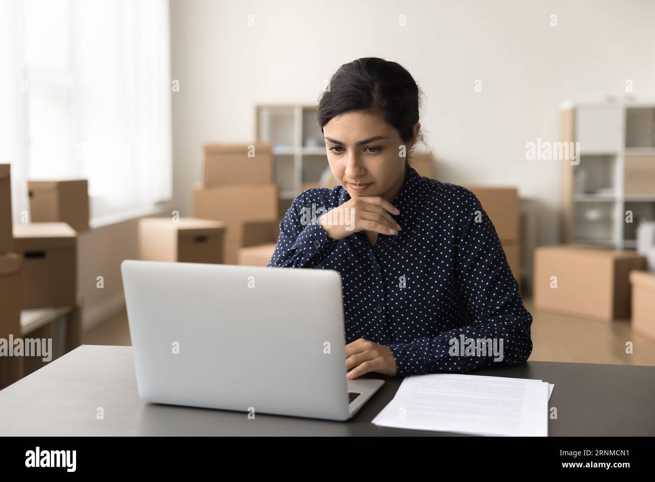 Ernsthafte, schöne indische Geschäftsfrau, die an einem Internet-Store-Startup arbeitet Stockfoto