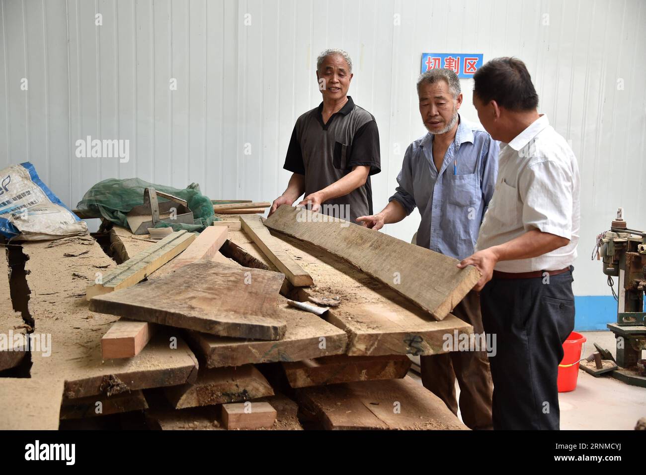 (170523) -- JINAN, 23. Mai 2017 -- Zhao Shuhuan (C) und seine Kollegen wählen Materialien in seiner Werkstatt im Dorf Dongtai der Gemeinde Zhutai in Zibo, ostchinesische Provinz Shandong, 22. Mai 2017 aus. Der 54-jährige Zhao hat seit seiner Kindheit eine Beinbehinderung. Als Zhao älter wurde und die Nachfrage nach Tischlerei zurückging, geriet er in die Armut. Vor zwei Jahren half die örtliche Armutsbekämpfungsabteilung Zhao, eine Werkstatt zu bauen und Schneid- und Poliermaschinen als eine gezielte Maßnahme in Armutsbekämpfungskampagnen zu kaufen. Es fand auch einen Stand auf einem Möbelmarkt für ihn. Umsatzvolumen Stockfoto