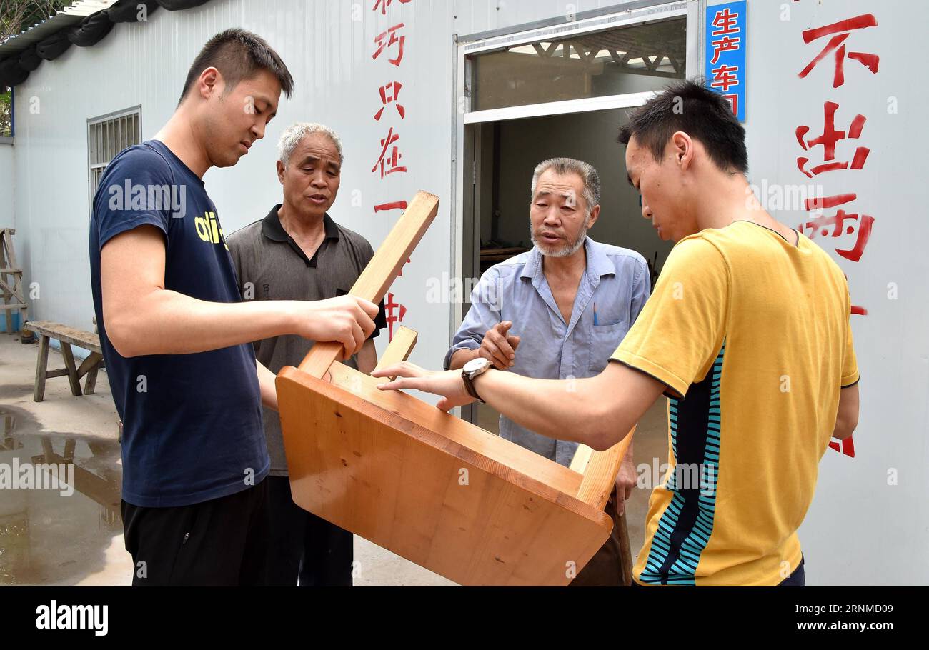 (170523) -- JINAN, 23. Mai 2017 -- Zhao Shuhuan (2. R) stellt technische Nachfrage in seiner Werkstatt im Dorf Dongtai der Gemeinde Zhutai in Zibo, ostchinesische Provinz Shandong, am 22. Mai 2017 vor. Der 54-jährige Zhao hat seit seiner Kindheit eine Beinbehinderung. Als Zhao älter wurde und die Nachfrage nach Tischlerei zurückging, geriet er in die Armut. Vor zwei Jahren half die örtliche Armutsbekämpfungsabteilung Zhao, eine Werkstatt zu bauen und Schneid- und Poliermaschinen als eine gezielte Maßnahme in Armutsbekämpfungskampagnen zu kaufen. Es fand auch einen Stand auf einem Möbelmarkt für ihn. Verkaufsmenge von Stockfoto