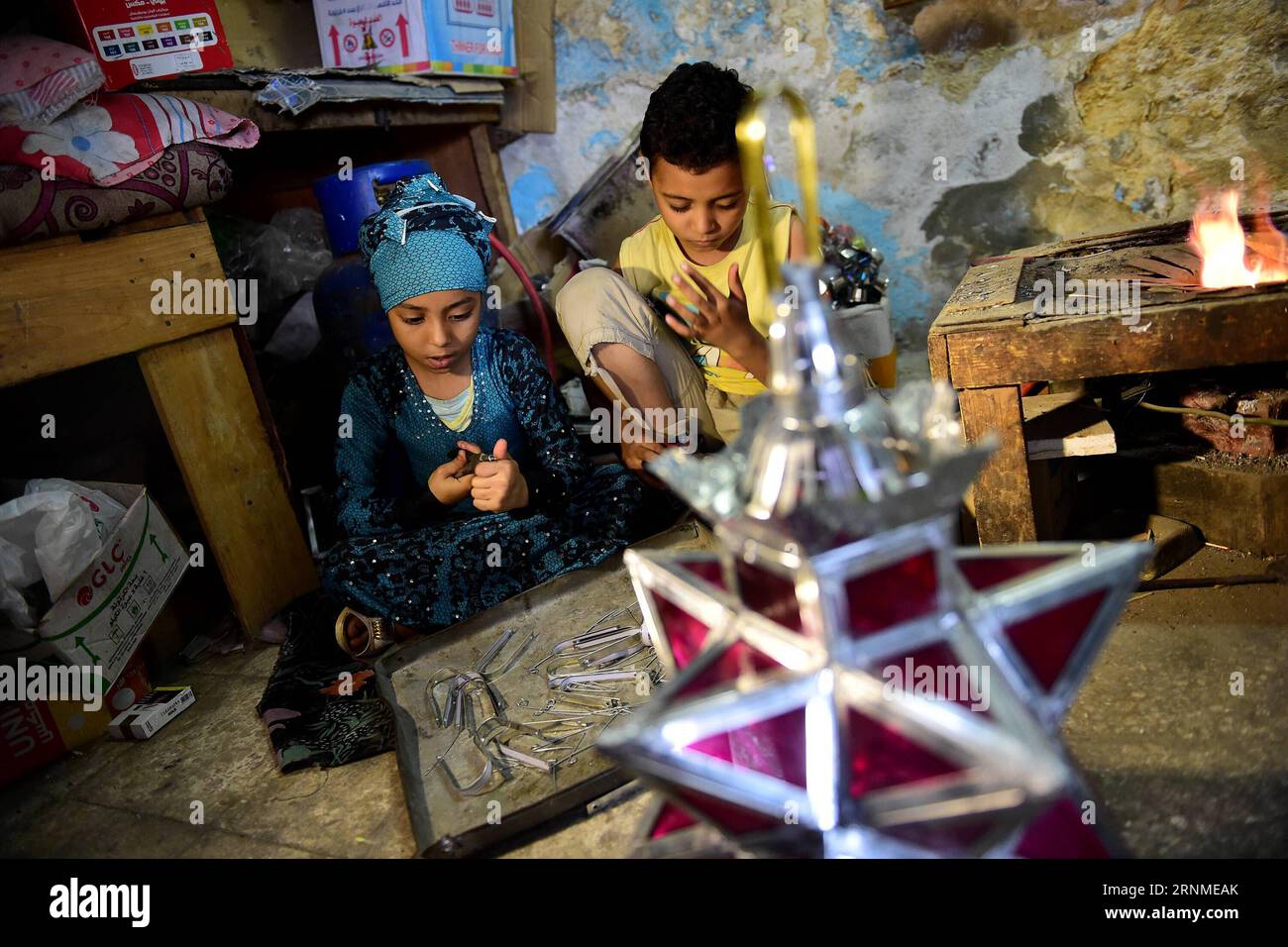 (170524) - KAIRO, 24. Mai 2017 -- Hussein Sayyids Kinder stellen am 20. Mai 2017 in der Werkstatt ihres Vaters in Kairo, Ägypten, traditionelle handgefertigte Laternen her. Sayyids Werkstatt befindet sich in einem alten Gebäude in einer Straße voller Werkstätten in Al-Qalaa, was die Zitadelle auf Arabisch bedeutet und sich auf Kairos Saladin-Zitadelle bezieht. Sayyids Werkstatt produziert bunte handgefertigte Glas- und Metalllaternen verschiedener Größen, die auf Arabisch als Fanoos bekannt sind und an Ständen vor der Werkstatt ausgestellt sind. Traditionelle handgefertigte Laternen dienen in Ägypten normalerweise während des jährlichen Ramadan-Monats als Dekoration. ) ÄGYPTEN-KAIRO-RAMADAN-HANDGEMACHTE LA Stockfoto