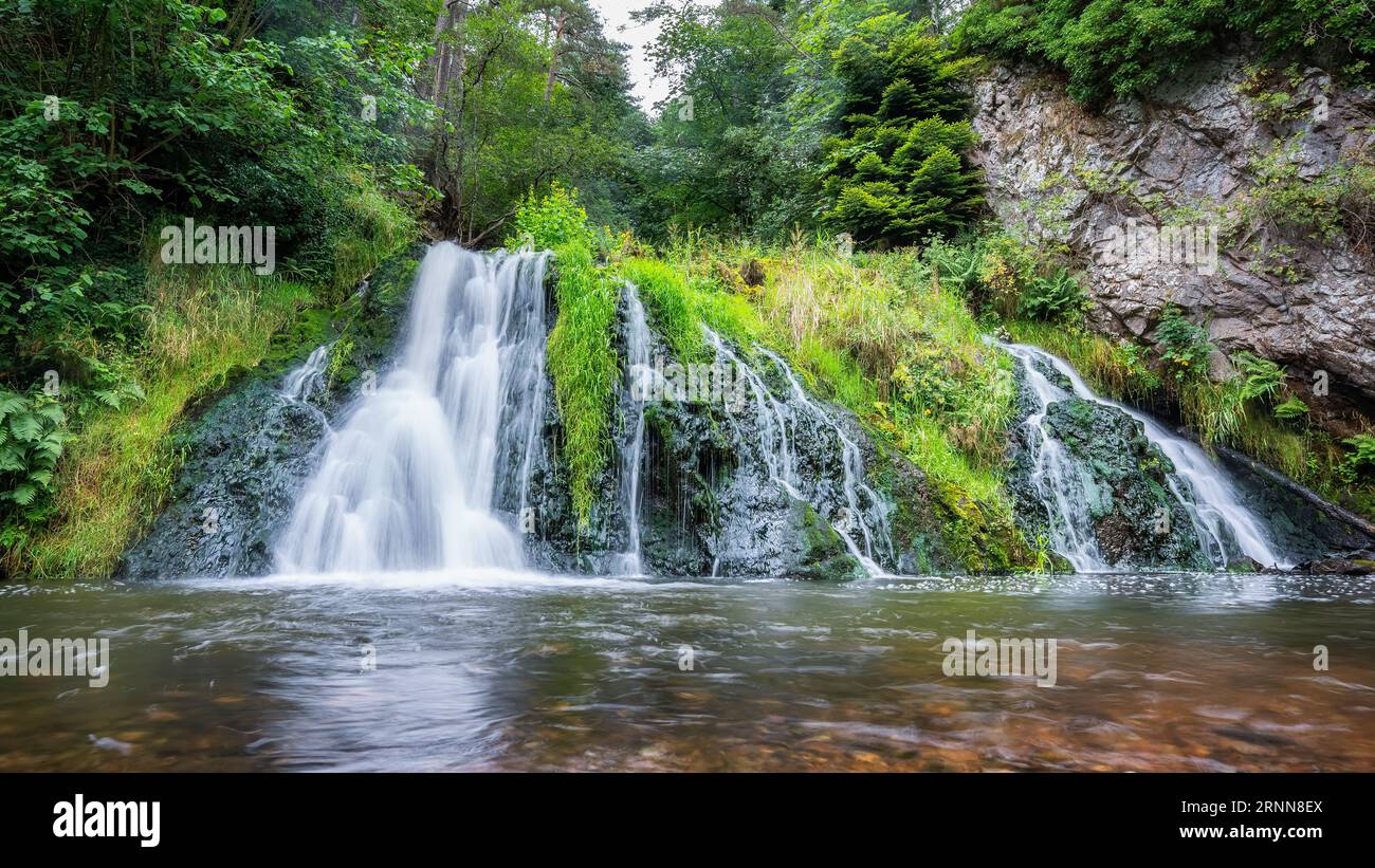 Kristallklarer Wasserfall umgeben von Grün in der Mitte der Highlands von Schottland, Großbritannien. Stockfoto