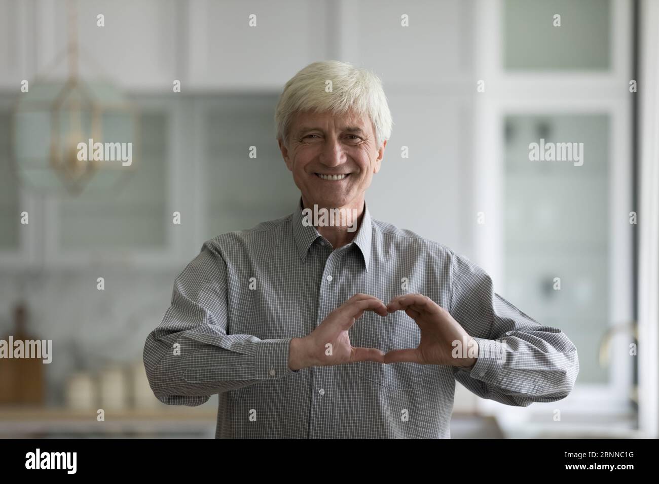 Glücklicher älterer Mann zeigt Hand Herz romantische Geste Stockfoto
