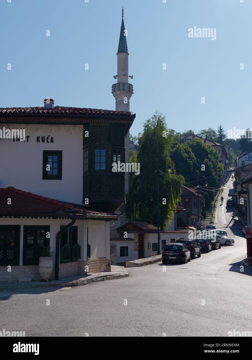 Restaurant Inat Kuca mit Minaret und steiler Straße dahinter in Sarajevo, Bosnien und Herzegowina, 2. September 2023 Stockfoto